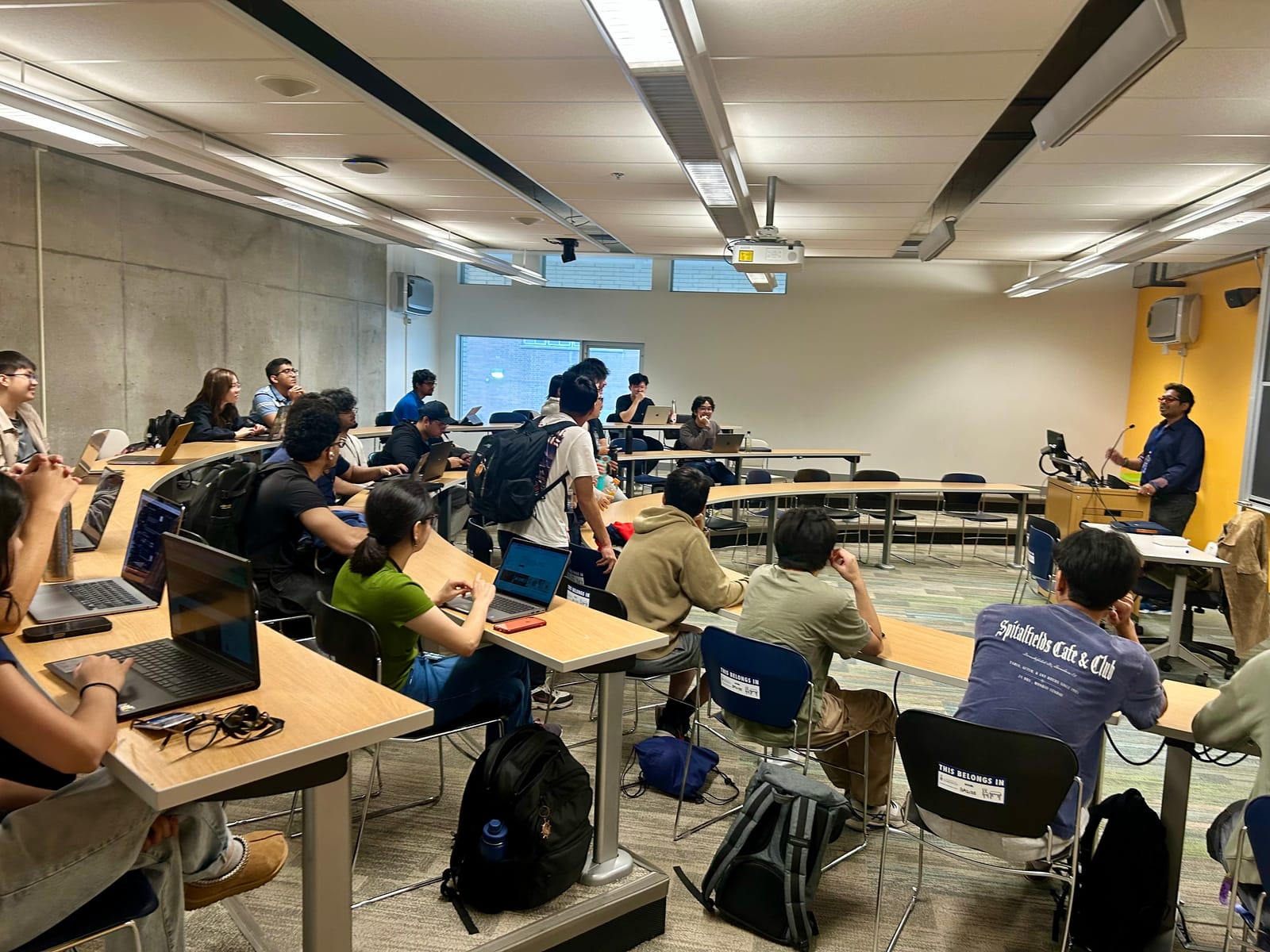 Workshop room at the Battle of the Schools: students at tiered desks with laptops facing a presenter at the front.