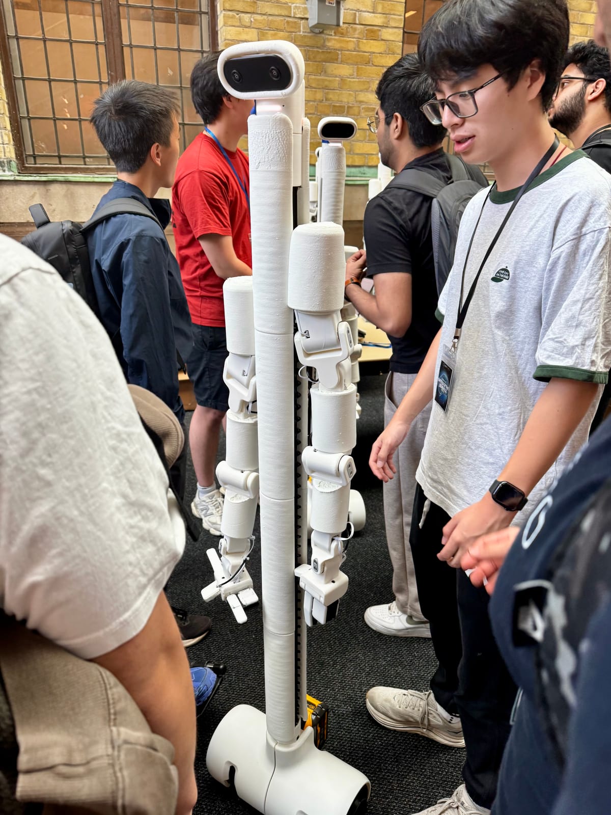 A humanoid robot standing among participants in the atrium.